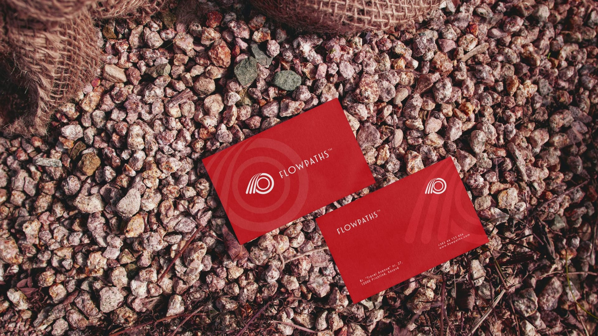 Two red Flowpaths business cards lying on gravel