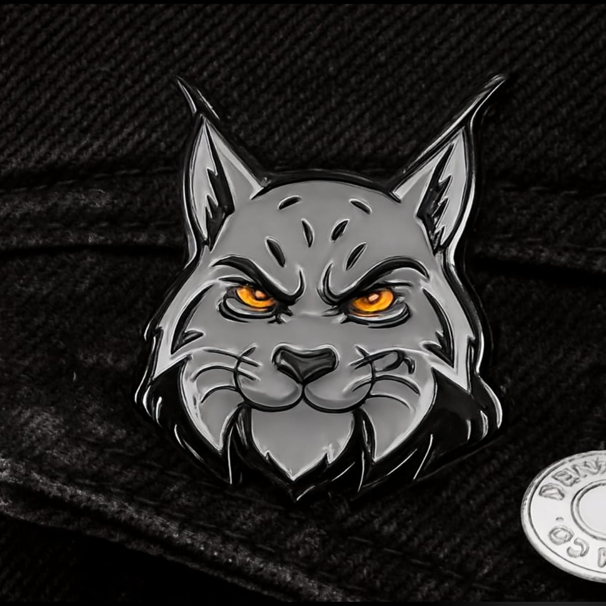 Metal pin of the lynx head on black fabric