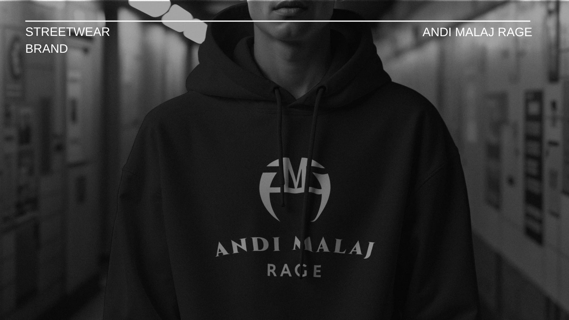 Person in a black Andi Malaj Rage hoodie, standing in a station corridor