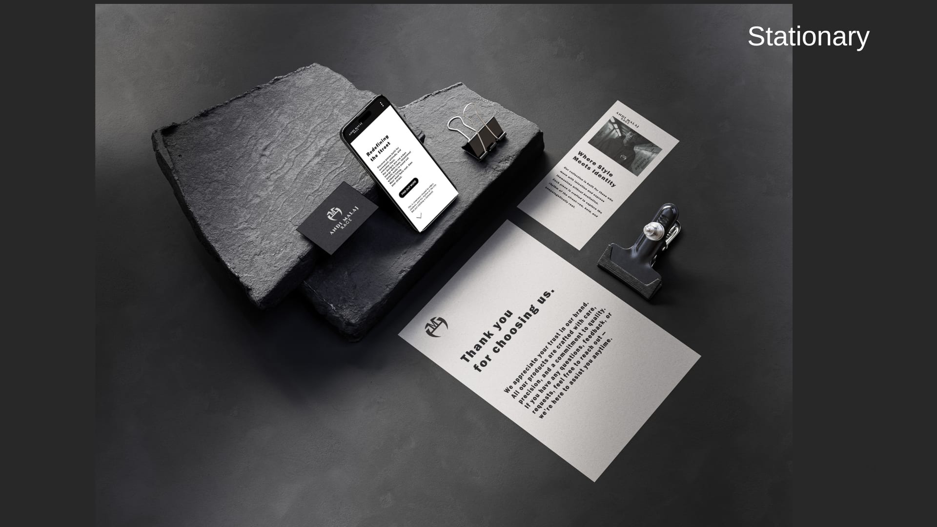 Andi Malaj Rage stationery, phone, and card on dark stone