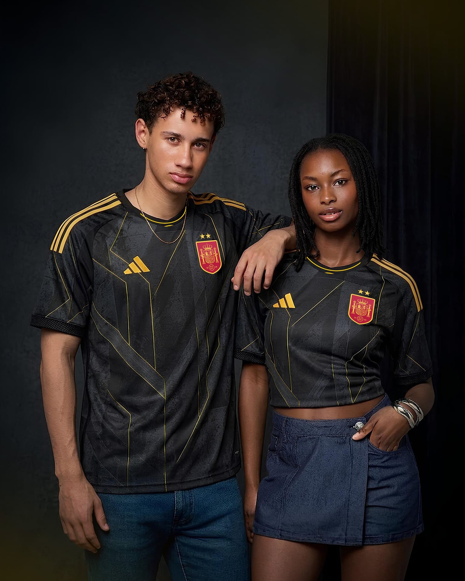 Two people wearing the black and yellow Spain away kit