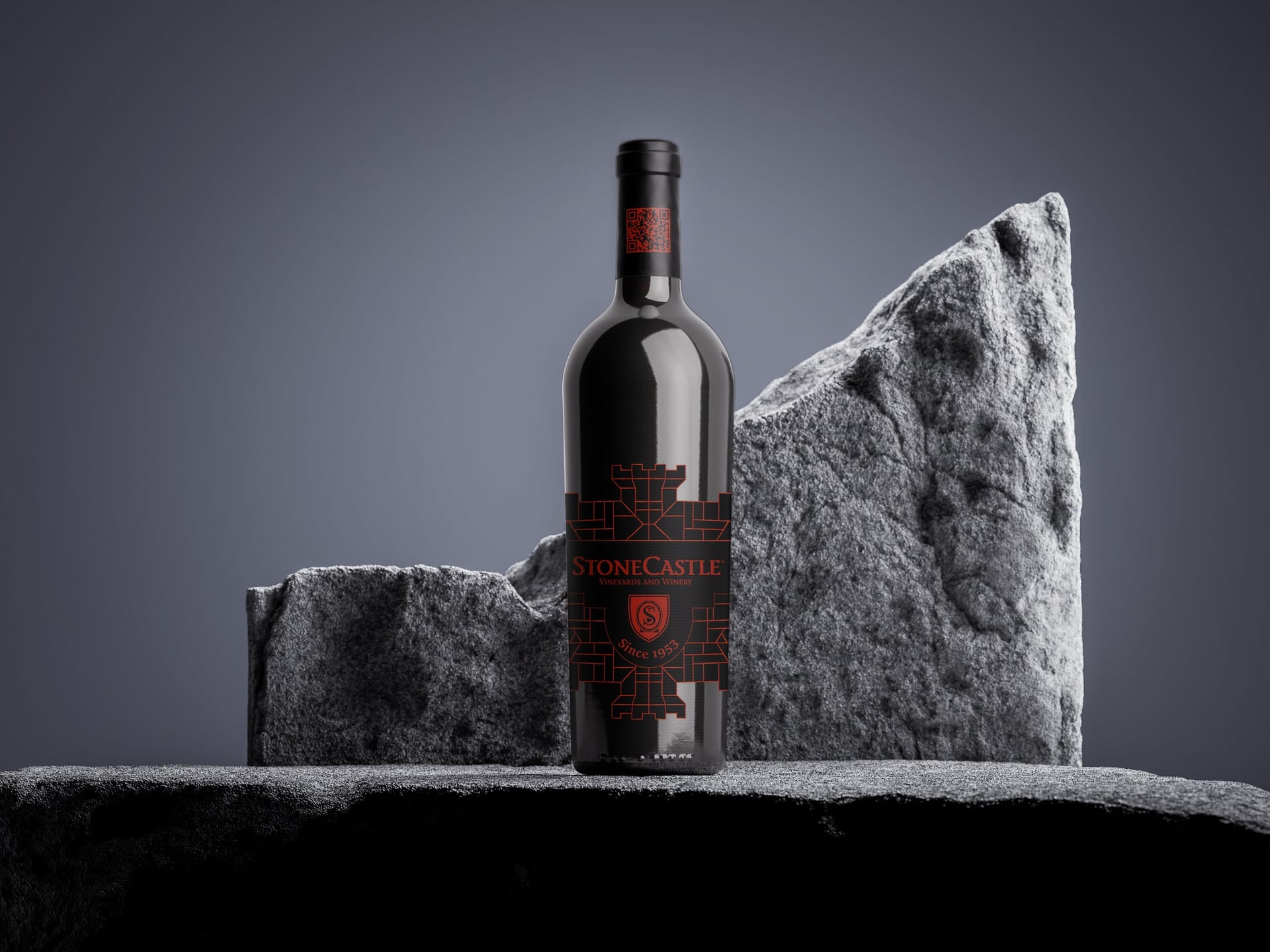 Black StoneCastle wine bottle with a red castle label, standing on dark stone